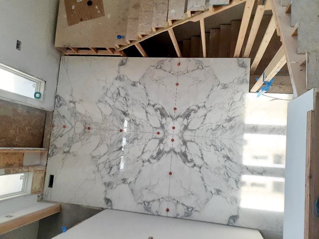 Large marble slab with symmetrical veining, in construction setting.