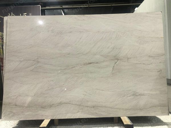 Large, light-colored stone slab with subtle veining and a glossy finish, likely for countertops.