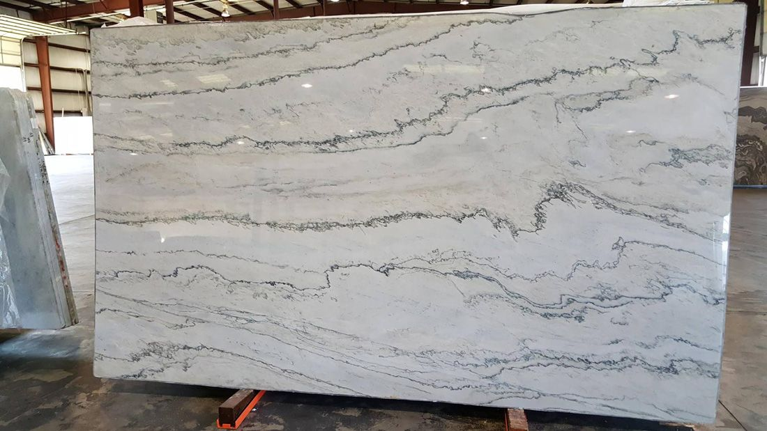 Large white marble slab with gray veining, displayed indoors.
