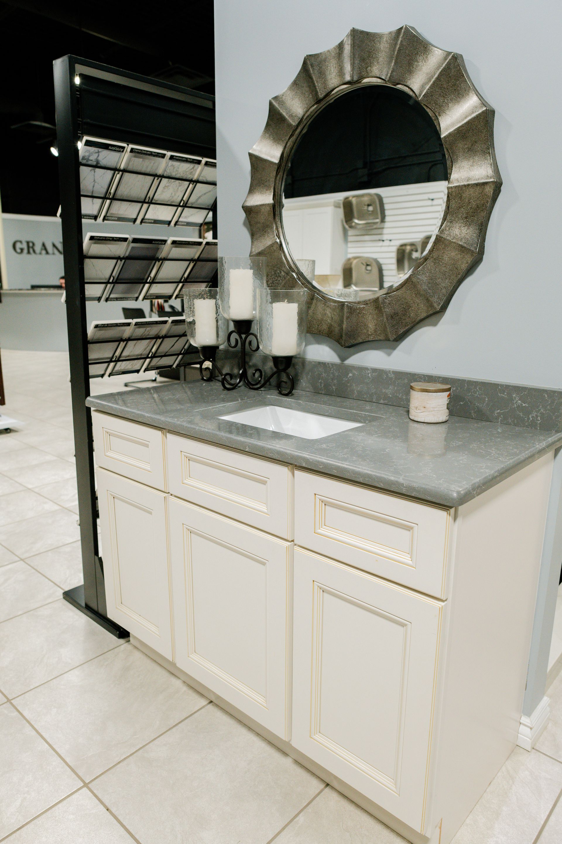 White bathroom vanity with gray countertop and round mirror 