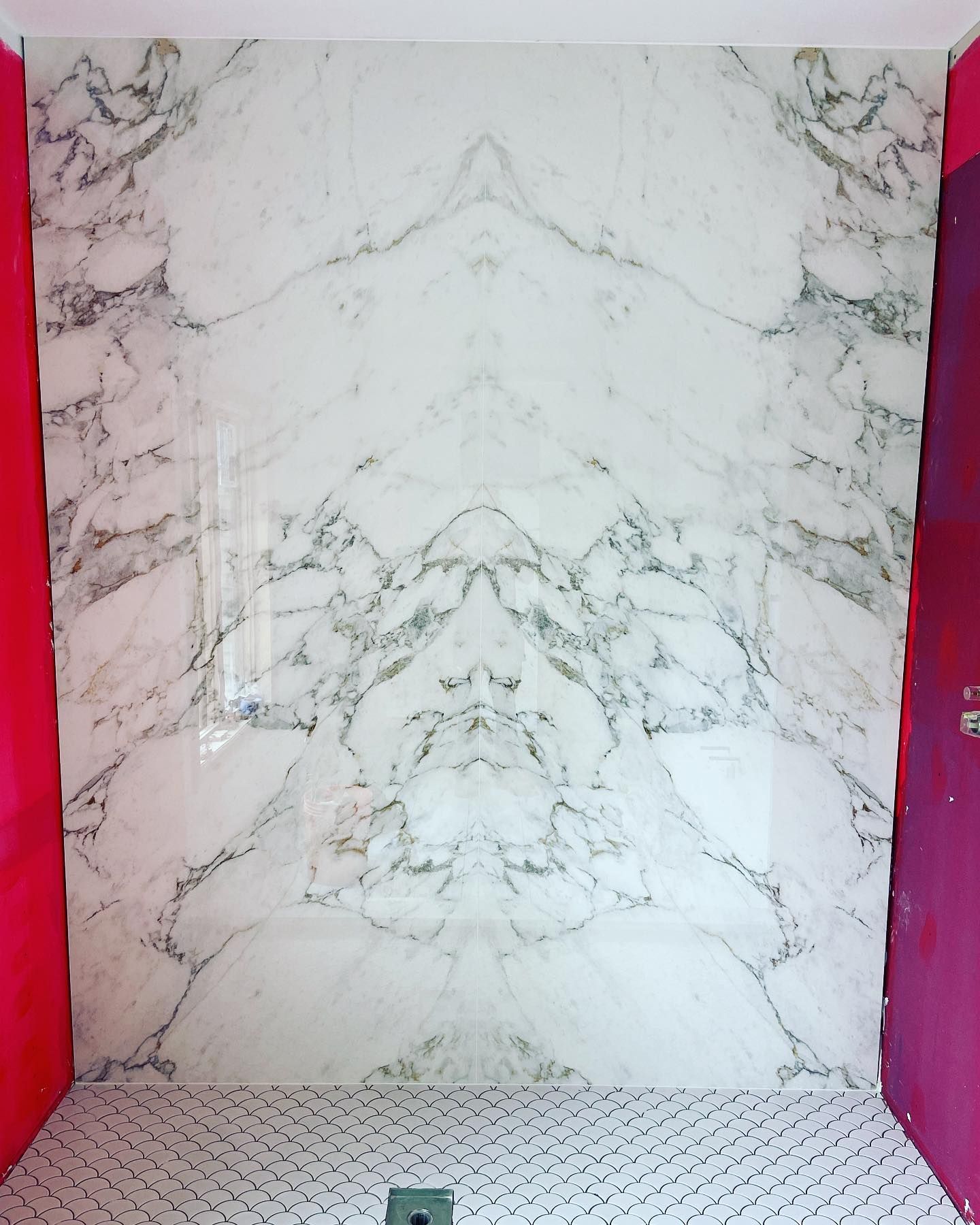 White marble-patterned wall panels with pink side walls and a perforated white floor.