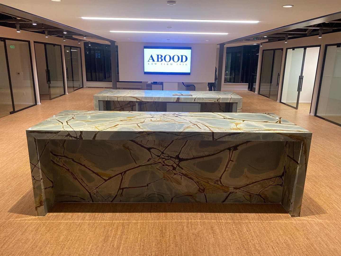 Marble reception desk in a modern lobby with an ABODO sign on a screen in the back.