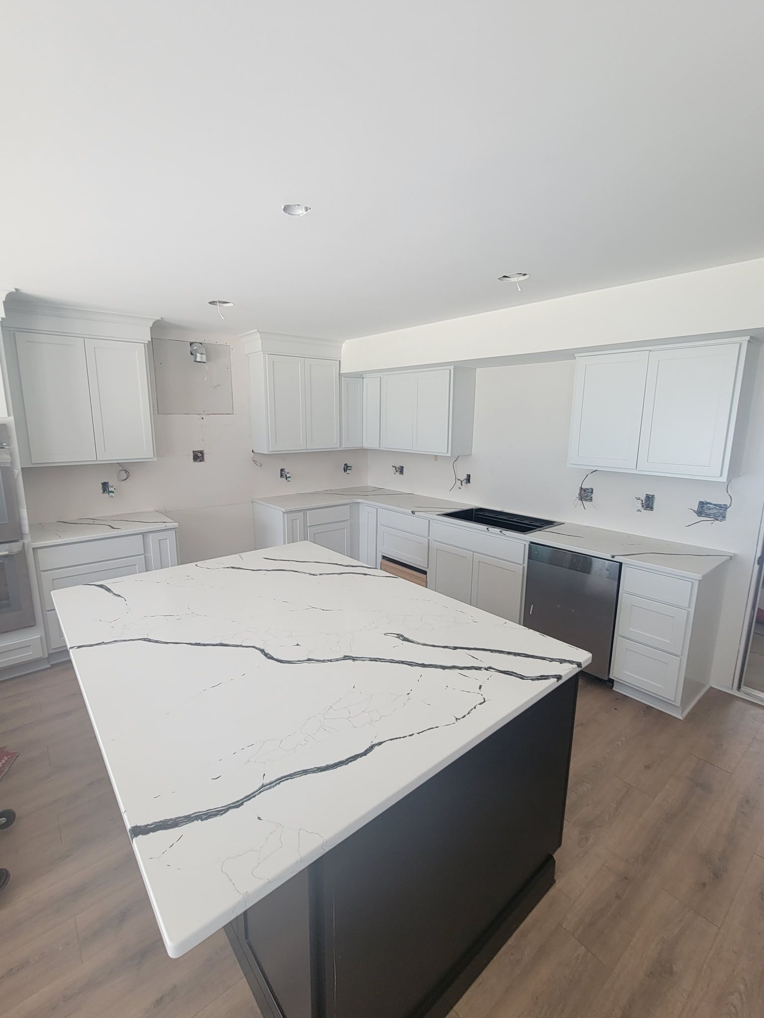 Bright modern kitchen with white cabinets, marble island, and wood flooring