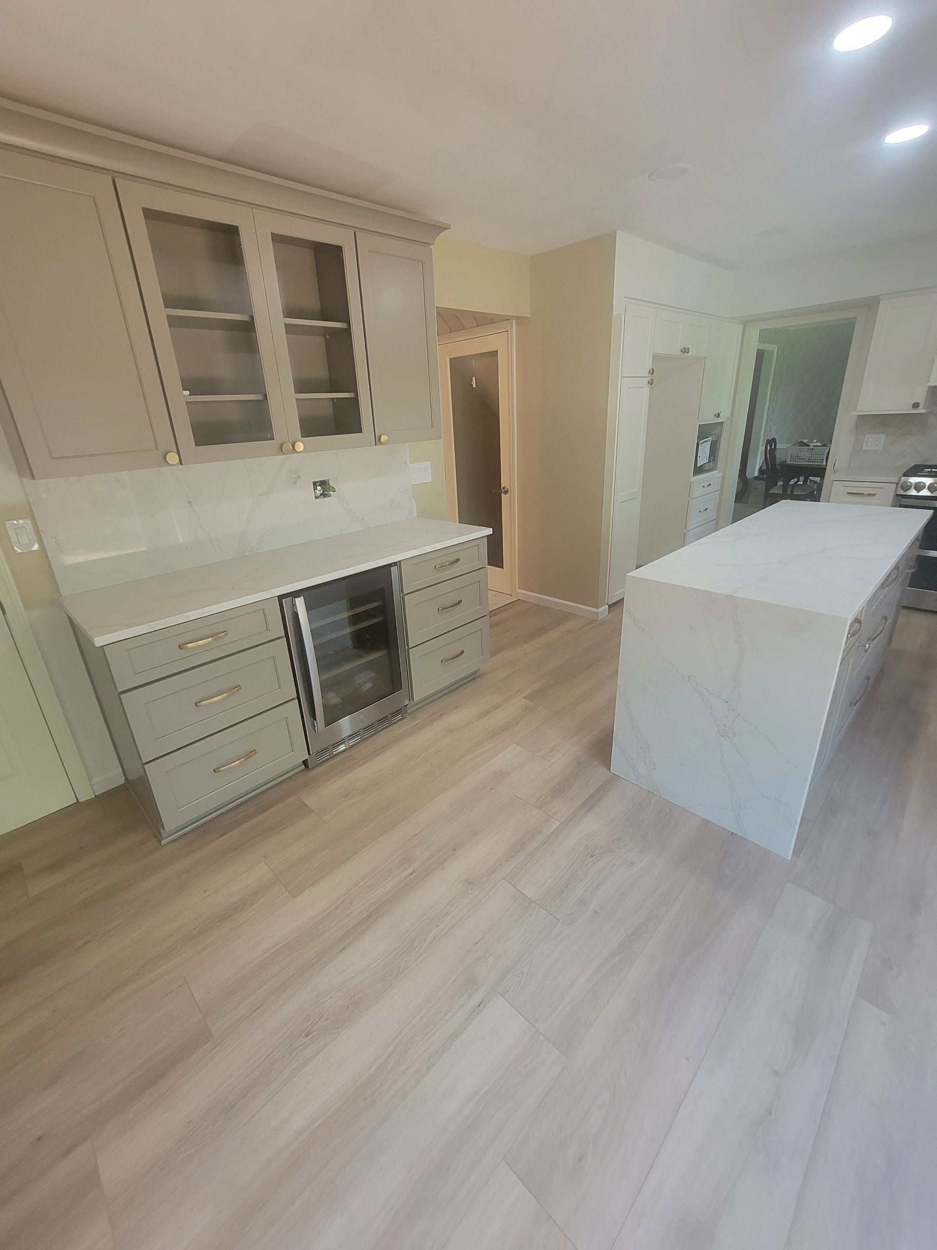 Bright modern kitchen with white cabinets, island, and light wood flooring