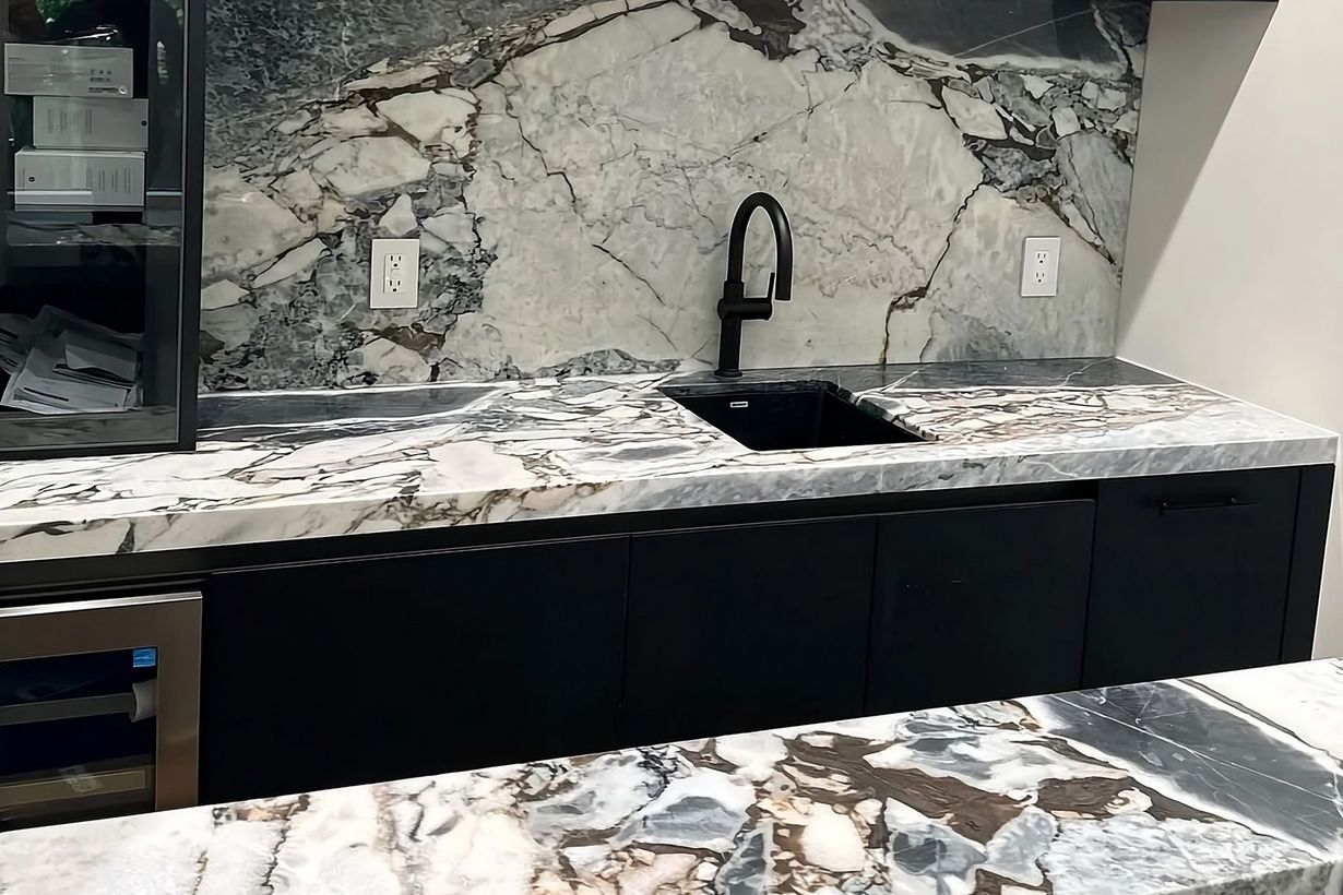 Modern kitchen with marble-pattern shelves, black cabinets, sink, and matching stone countertop