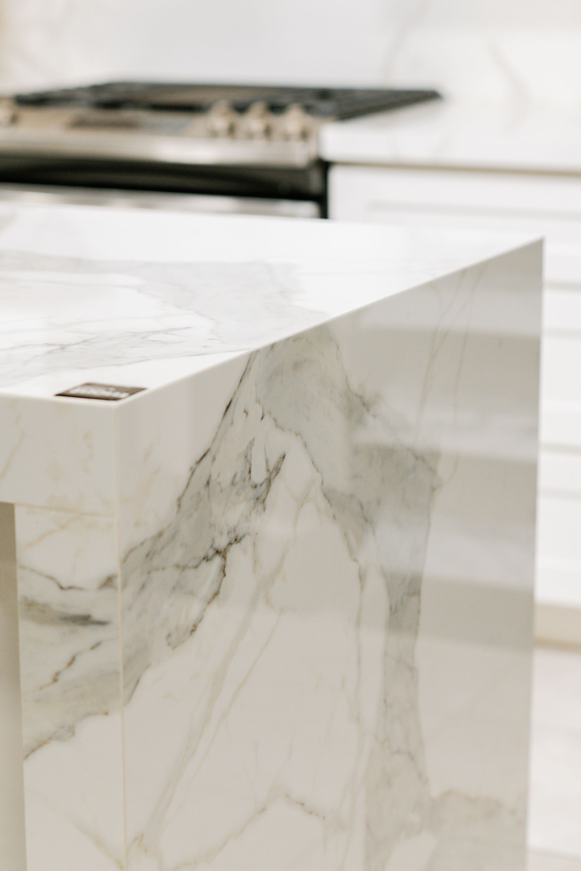 Marble waterfall kitchen island with white veining in a bright modern kitchen