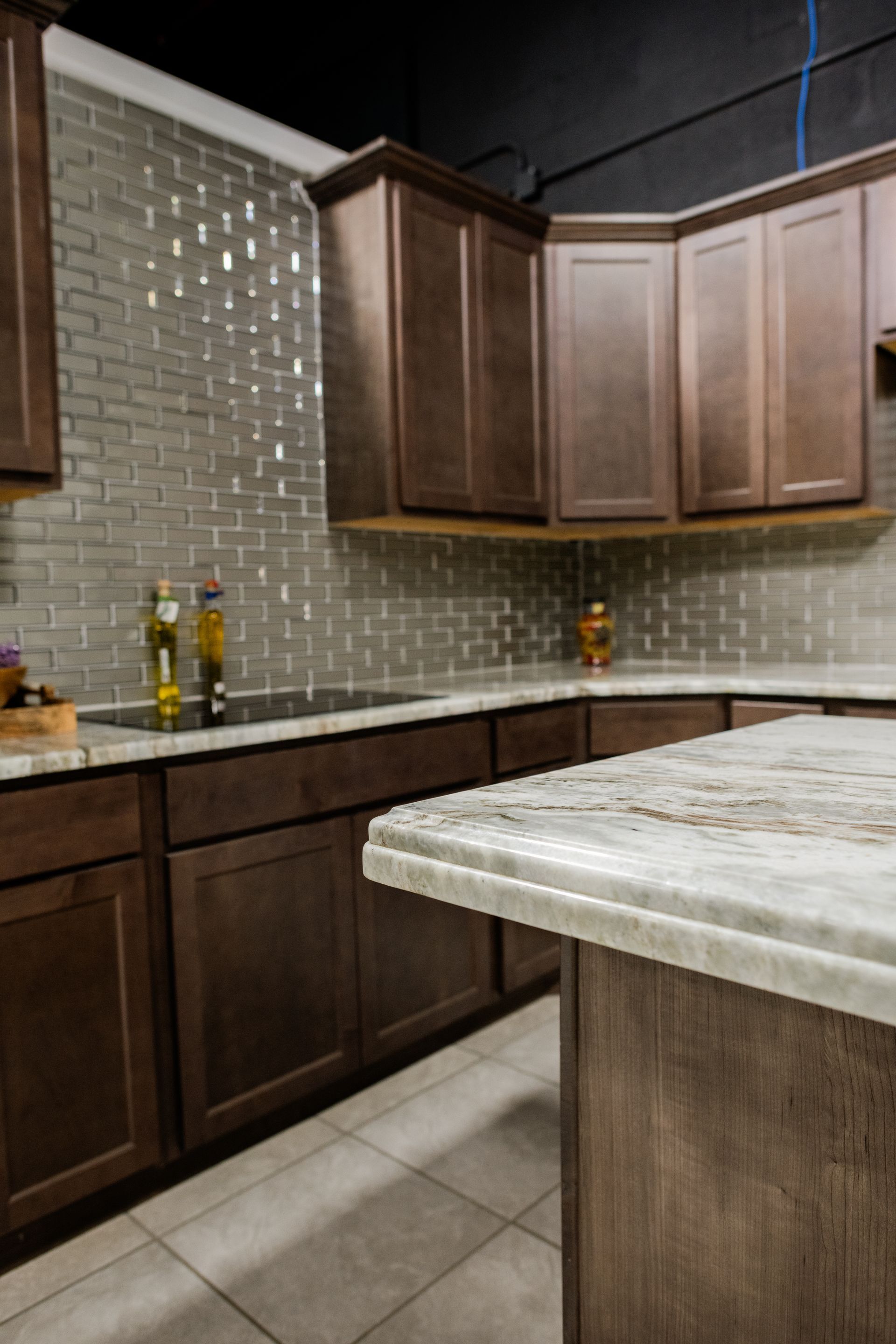 Modern kitchen with dark wood cabinets, mosaic backsplash, and marble-topped island.