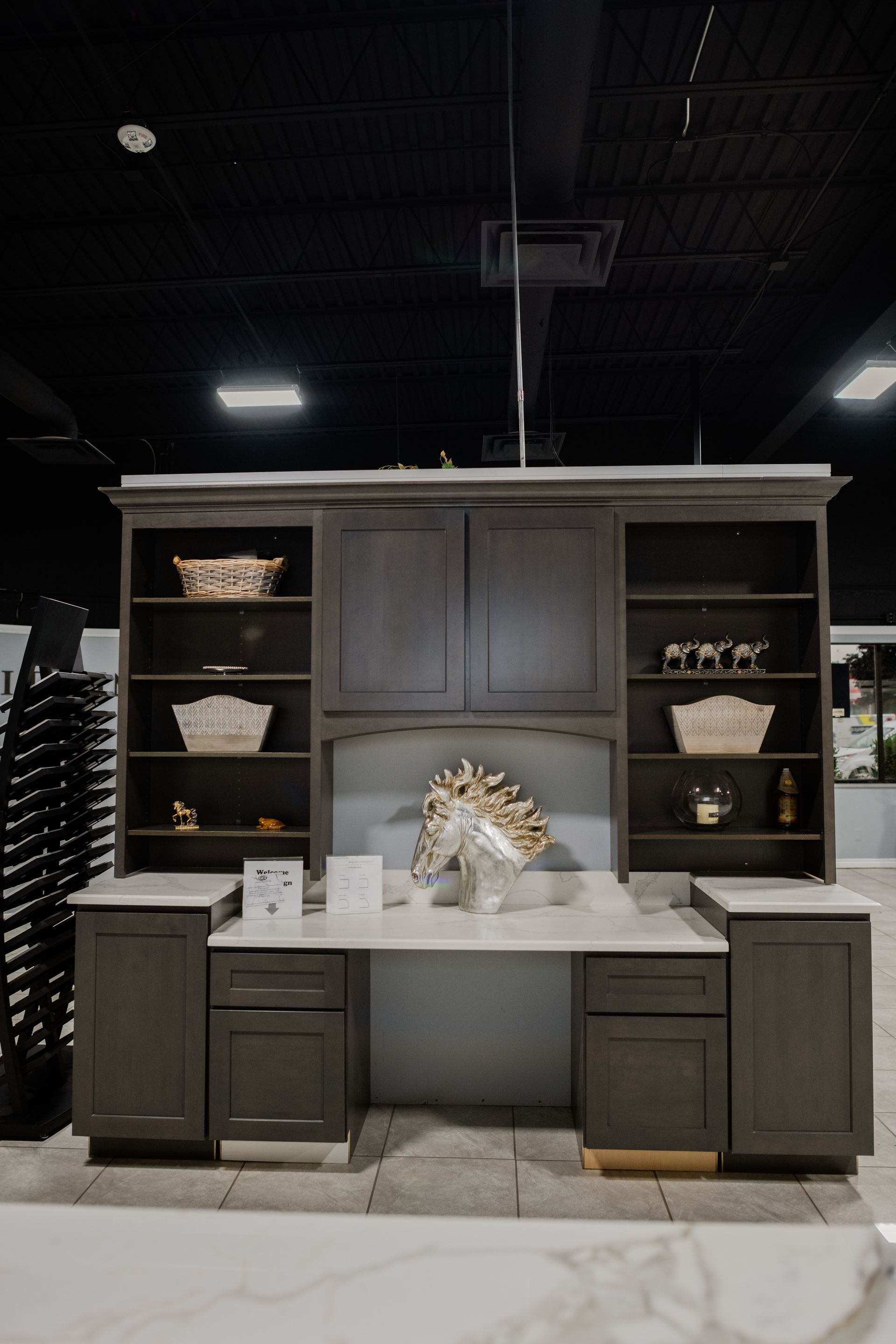 Dark wood kitchen display with shelves, cabinets, and a center island in a showroom