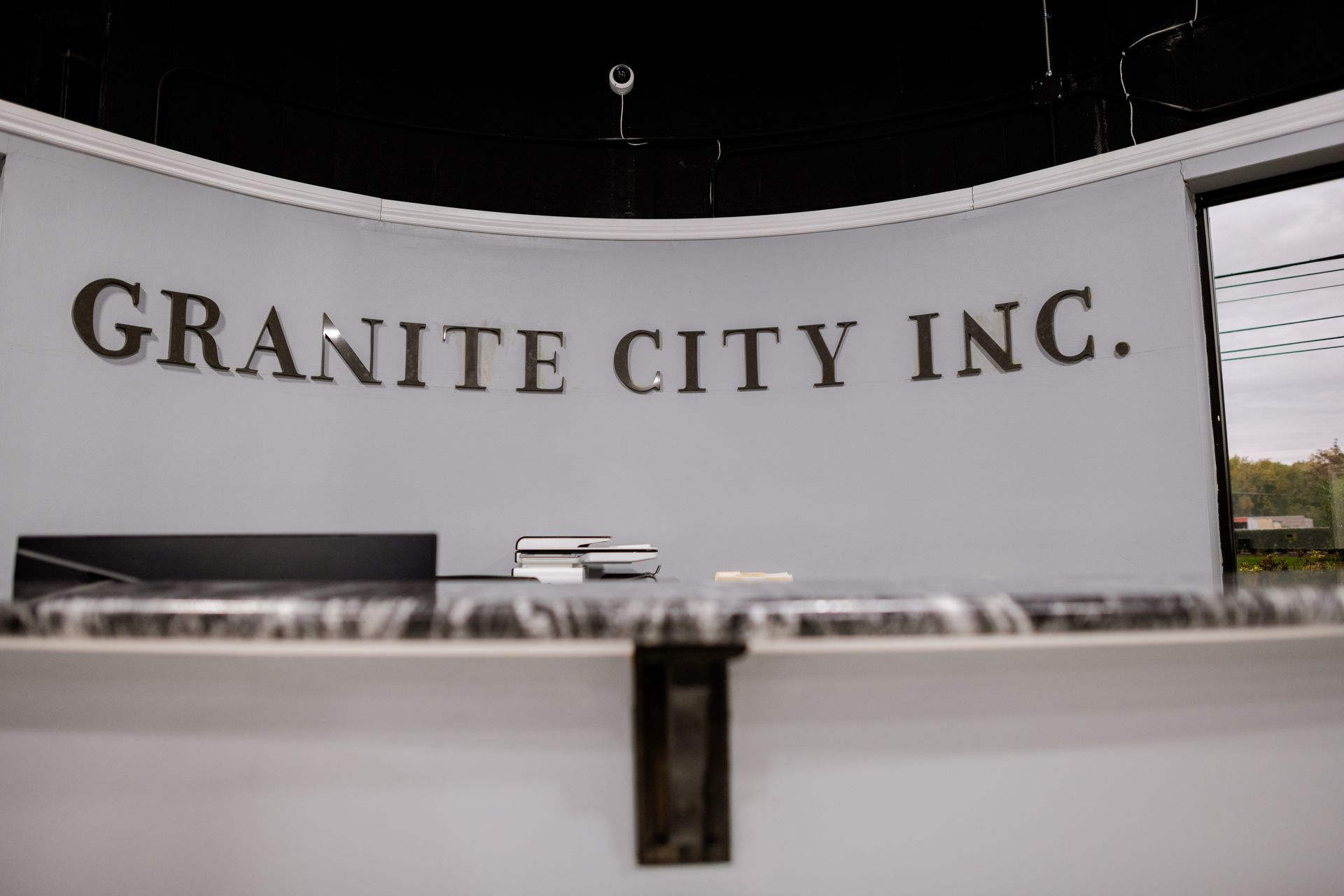 Granite City Inc's sign on a curved white wall 