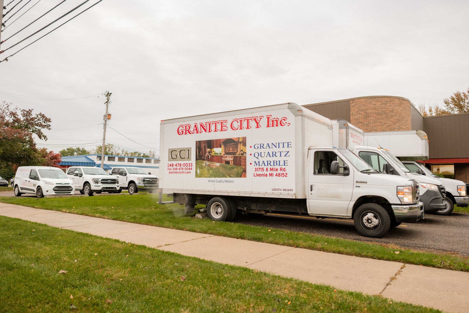 Granite City Inc's trucks parked beside a sidewalk on a cloudy day