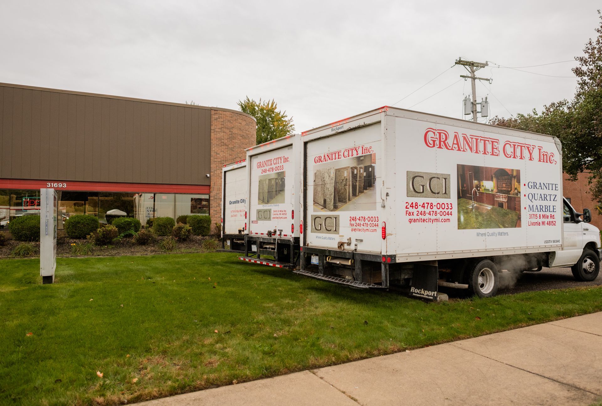Granite City Inc's three white trucks parked outside a building