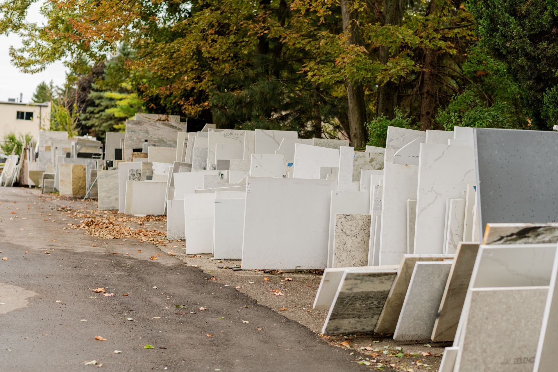 Rows of stone slabs lined along a roadside under trees