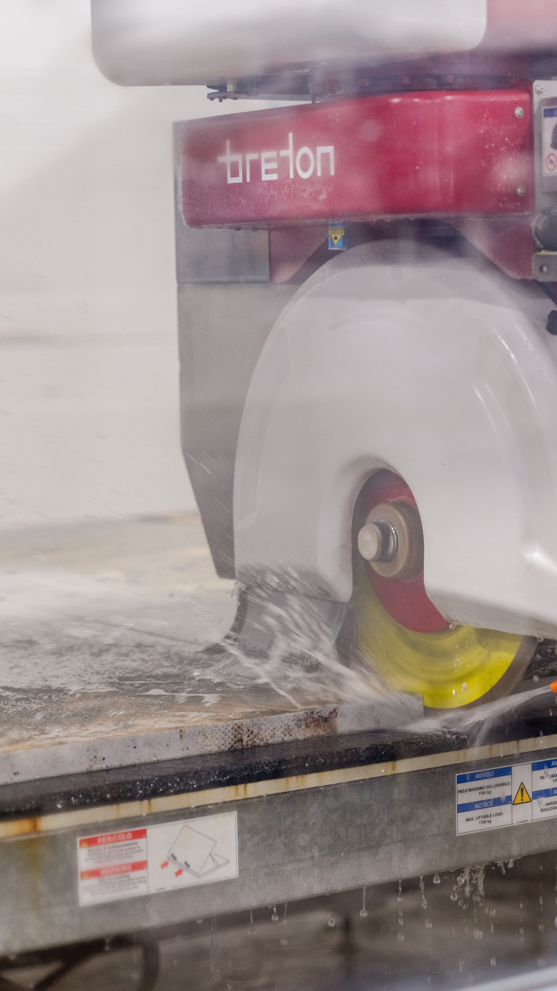 Industrial machine cutting material with water spray behind a protective shield