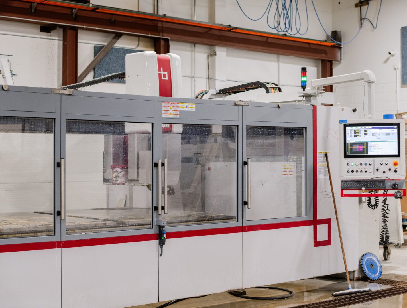 Industrial machine with clear safety enclosure and control panel in a factory workshop.