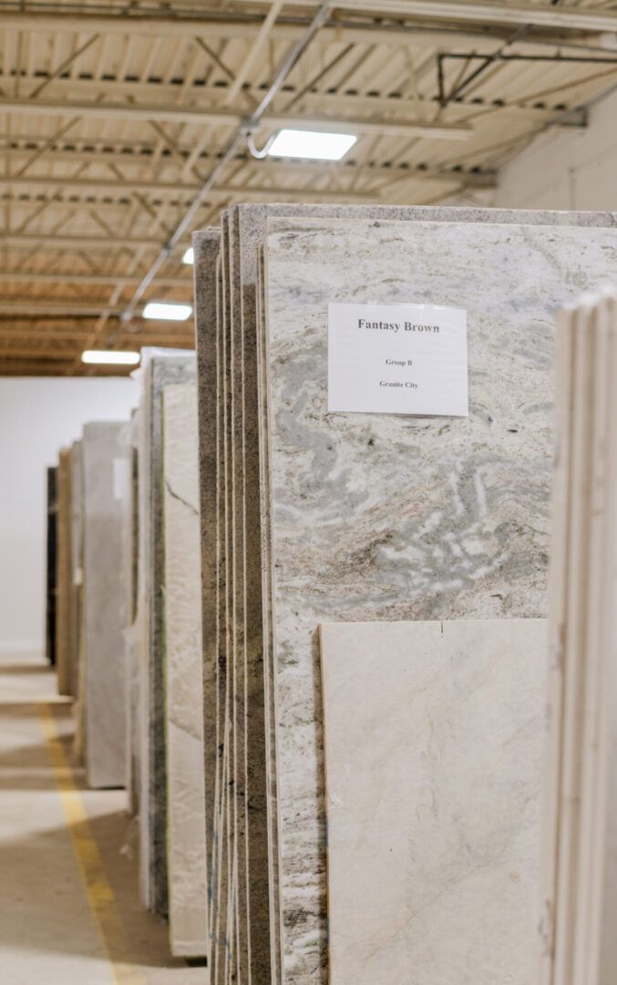 Rows of large polished stone slabs in a warehouse aisle with a paper label on the front slab