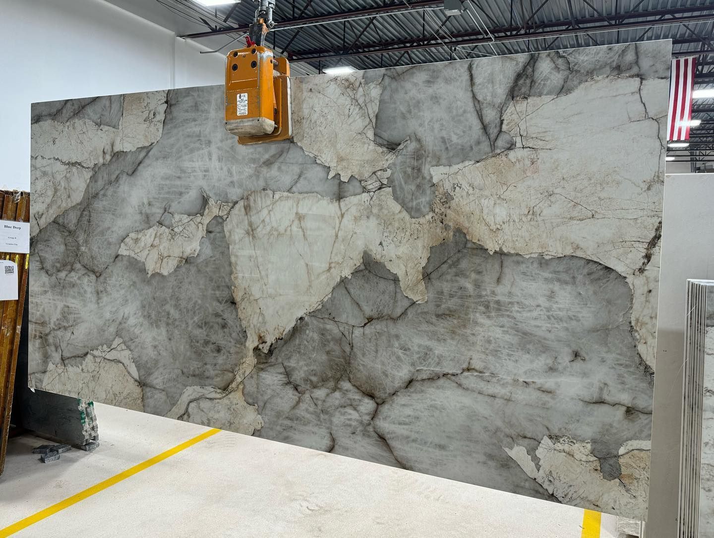 Cracked gray concrete wall in an indoor industrial space with an orange electrical unit mounted above.