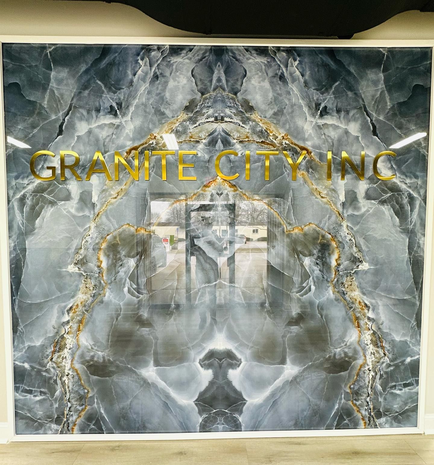 Granite City Inc gold text over a gray marble-patterned background with a central mirrored emblem