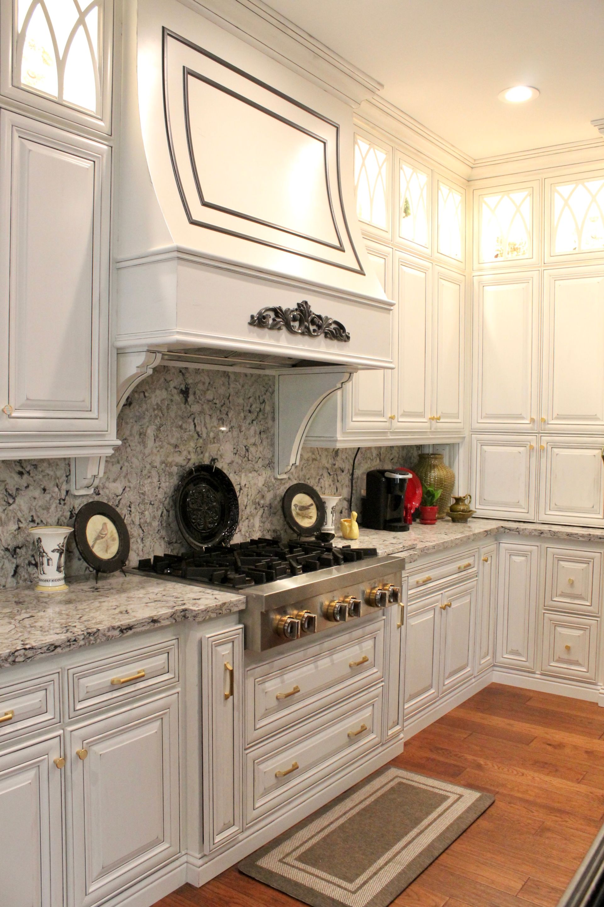 A kitchen with white cabinets , granite counter tops , and a stove top oven.