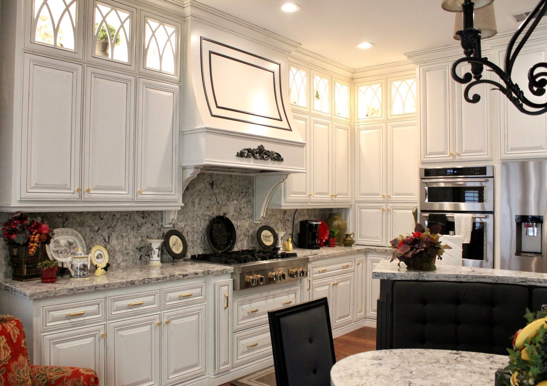 A kitchen with white cabinets , granite counter tops , stainless steel appliances , a table and chairs.