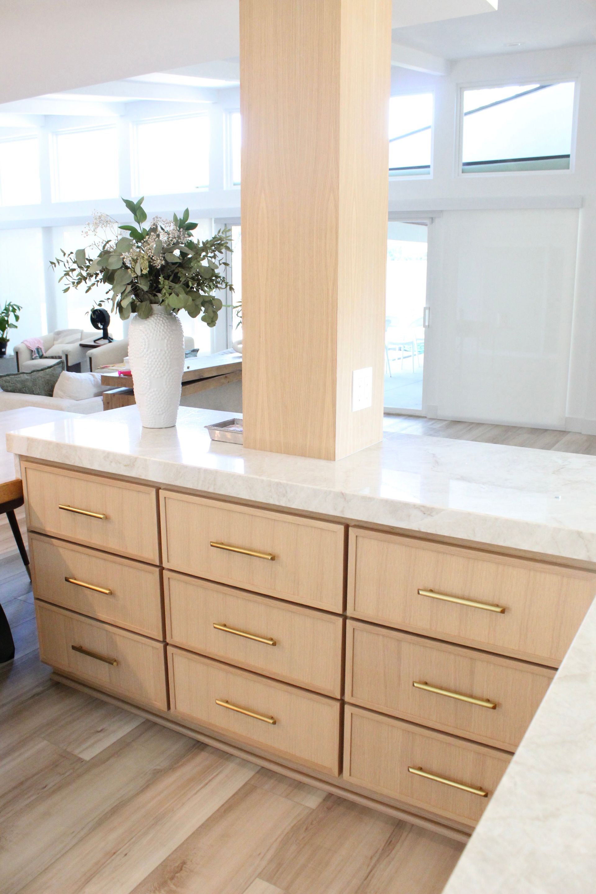 There is a vase of flowers on the counter in the kitchen.