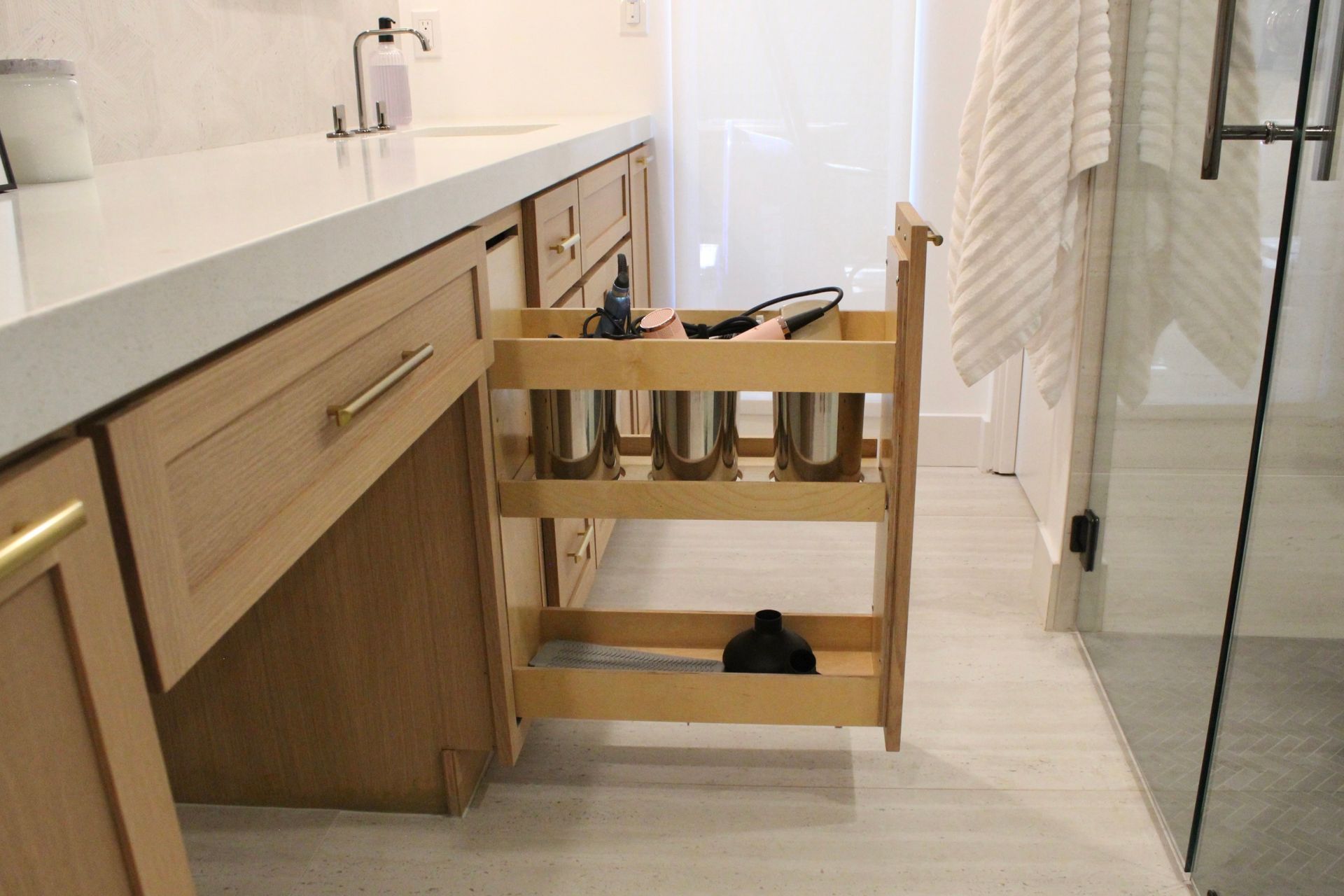 A bathroom with a pull out drawer filled with bottles.