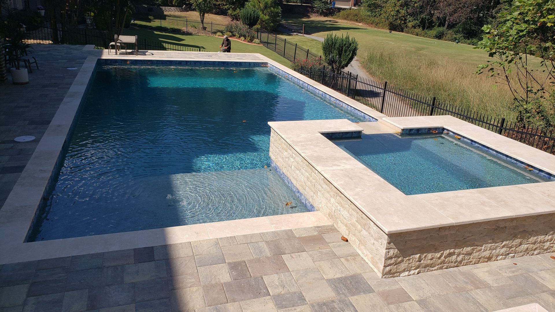 A large swimming pool with a hot tub next to it.