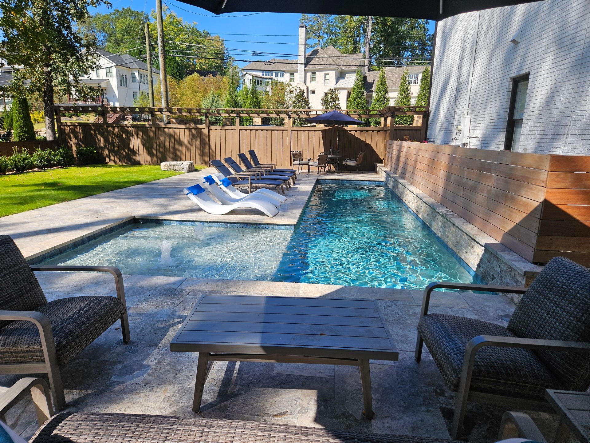 A swimming pool with chairs and a table in front of it