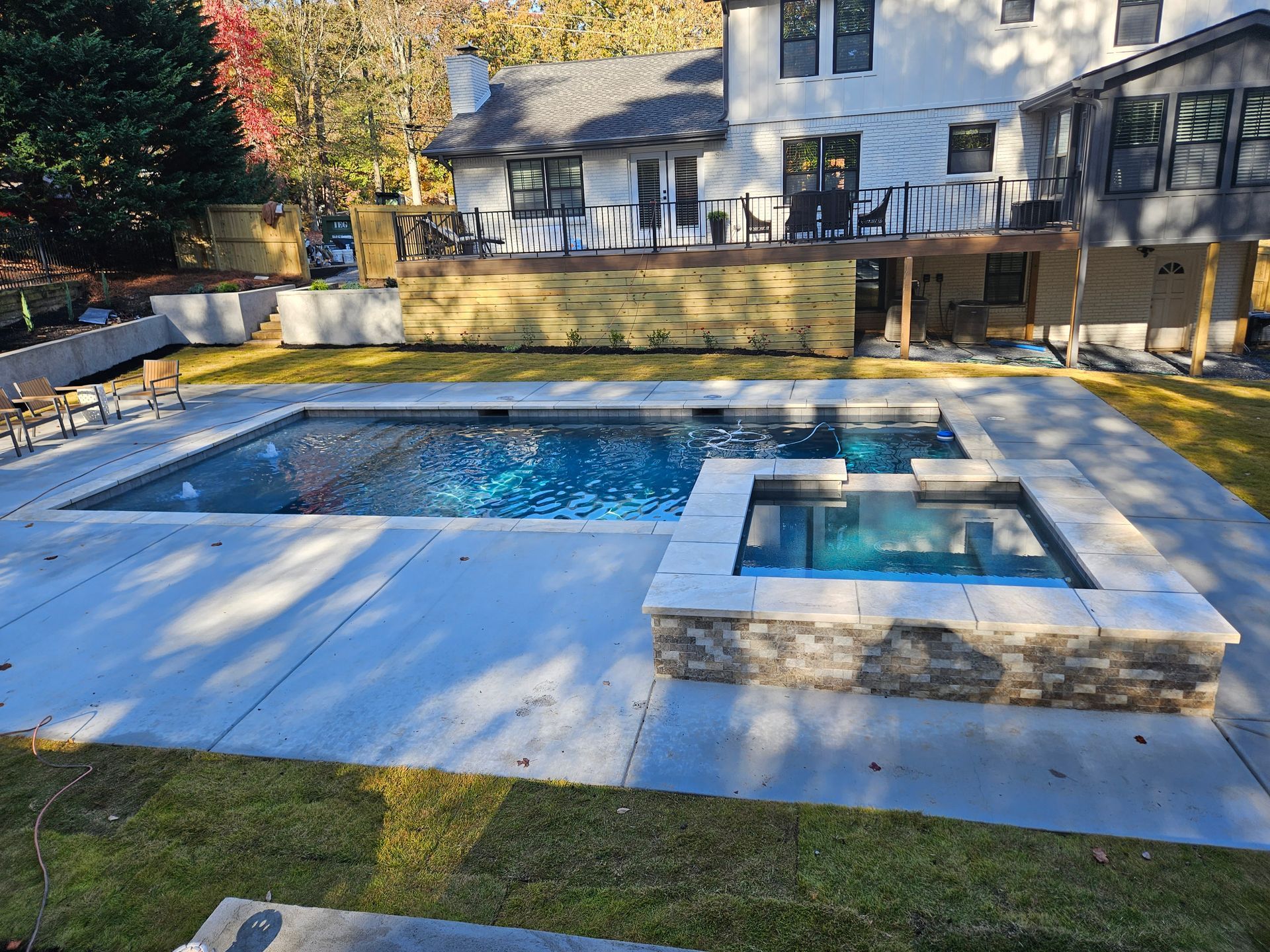 A large swimming pool with a hot tub in the backyard of a house.