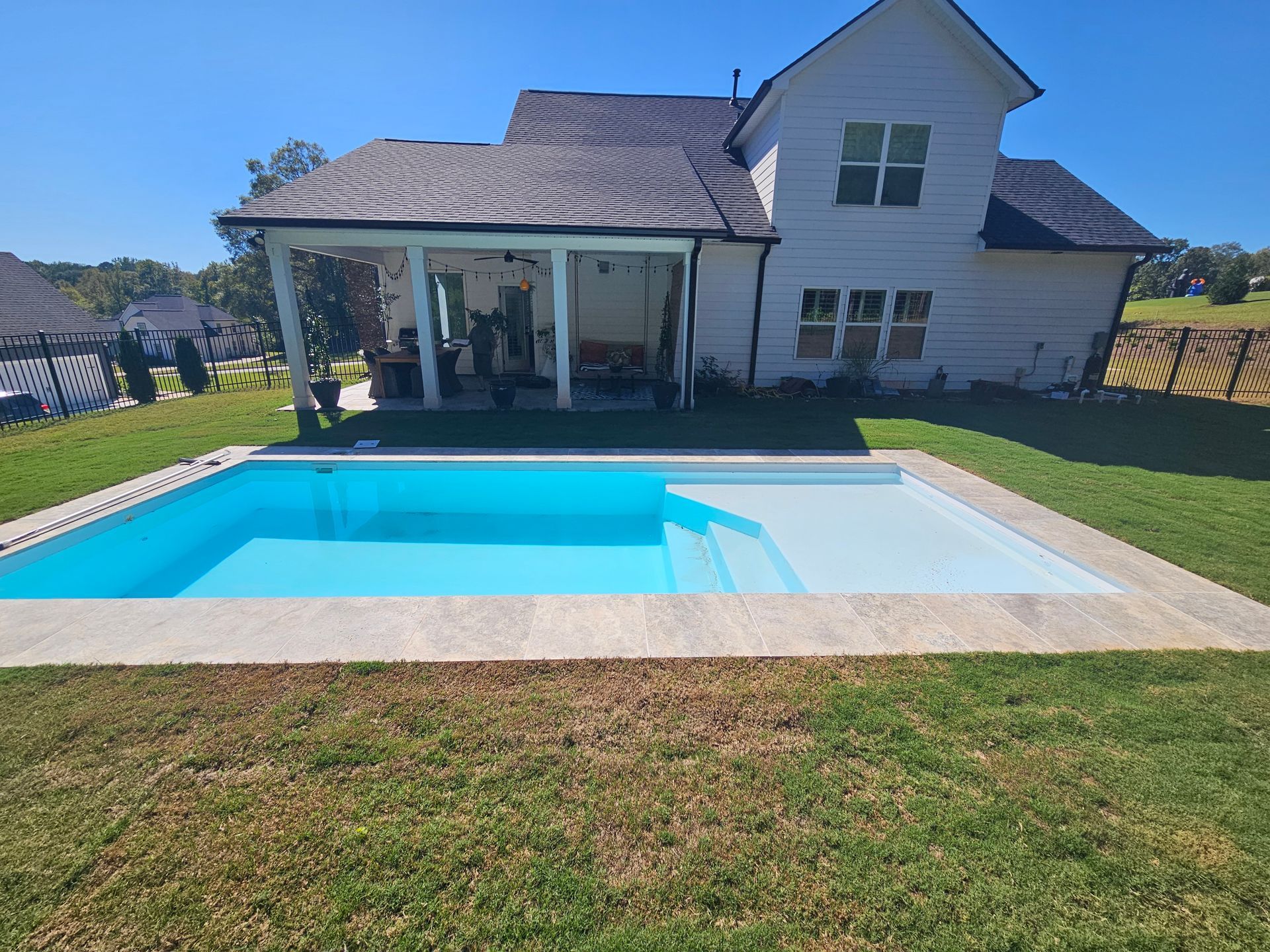 A large white house with a swimming pool in front of it.