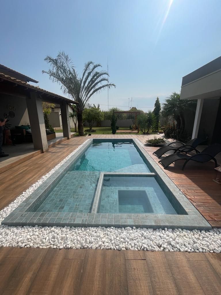 There is a large swimming pool in the backyard of a house.