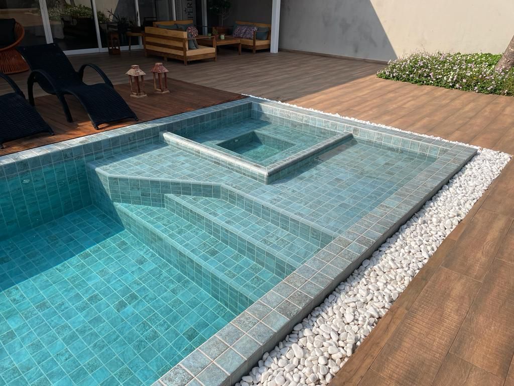 A large swimming pool with stairs and a hot tub in the middle of it.