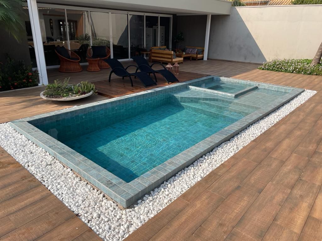 A large swimming pool is sitting on top of a wooden deck.