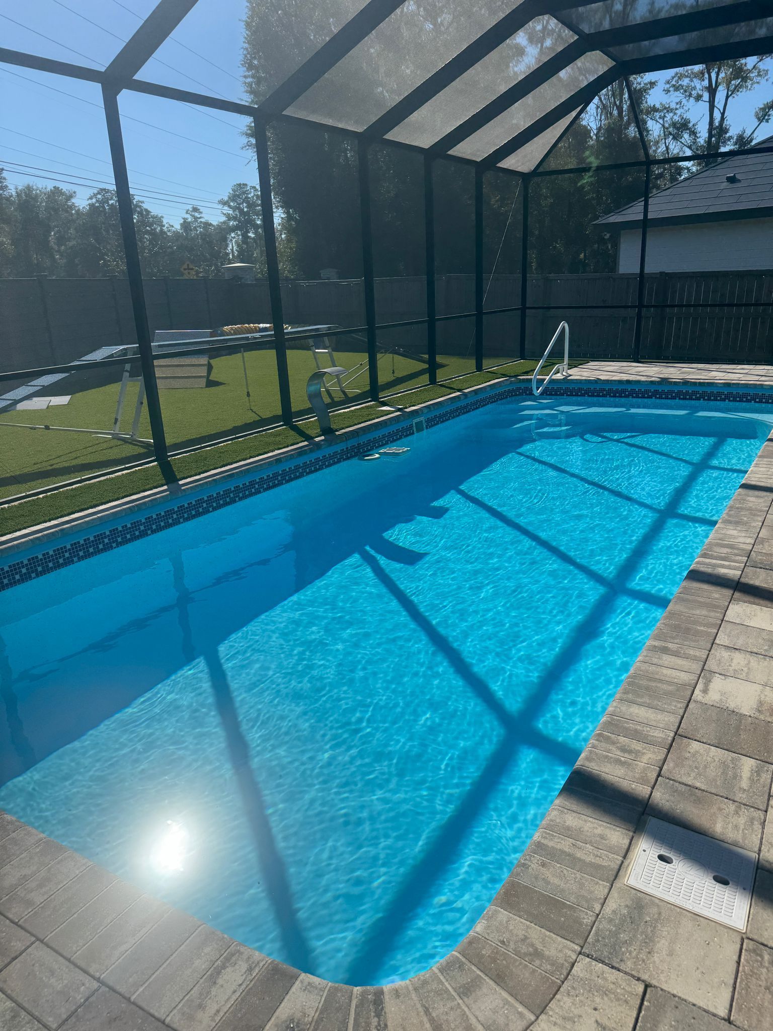 A large swimming pool with a screened in area in the backyard.