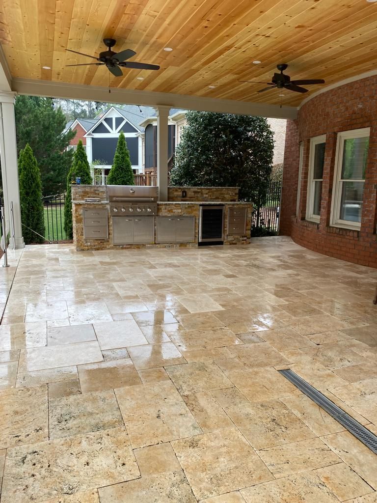 A large patio with a ceiling fan and a grill.