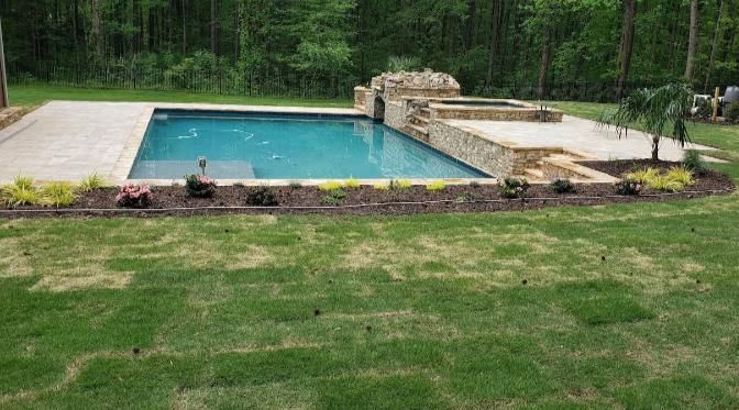 A large swimming pool is surrounded by a lush green lawn.