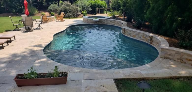 A large swimming pool in a backyard with a patio and chairs.