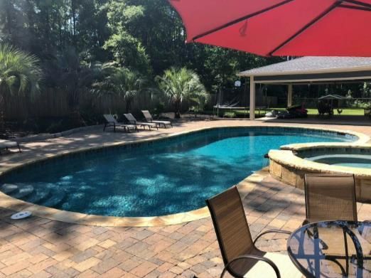 A large swimming pool with a red umbrella over it