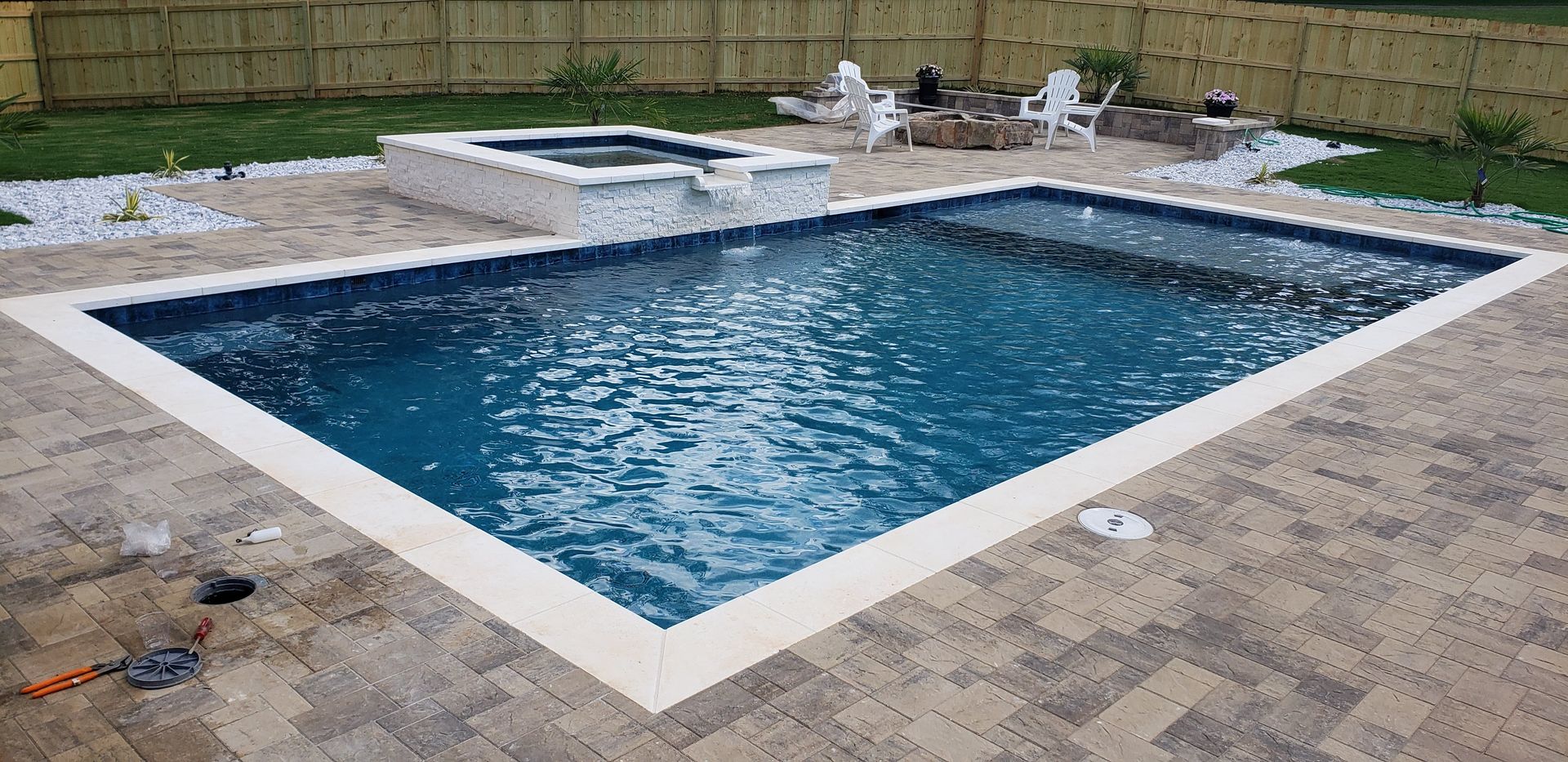 A large swimming pool is sitting on top of a brick patio.