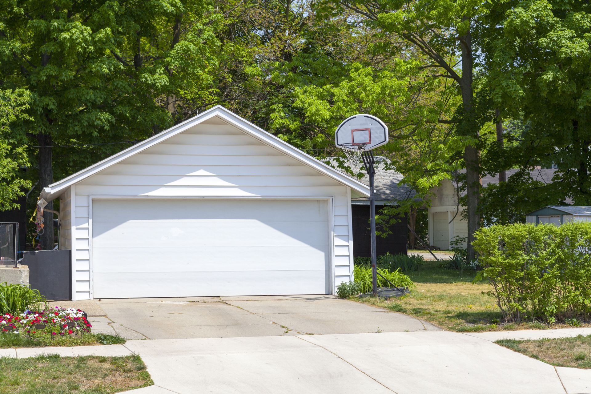 A white garage with a basketball hoop in front of it.