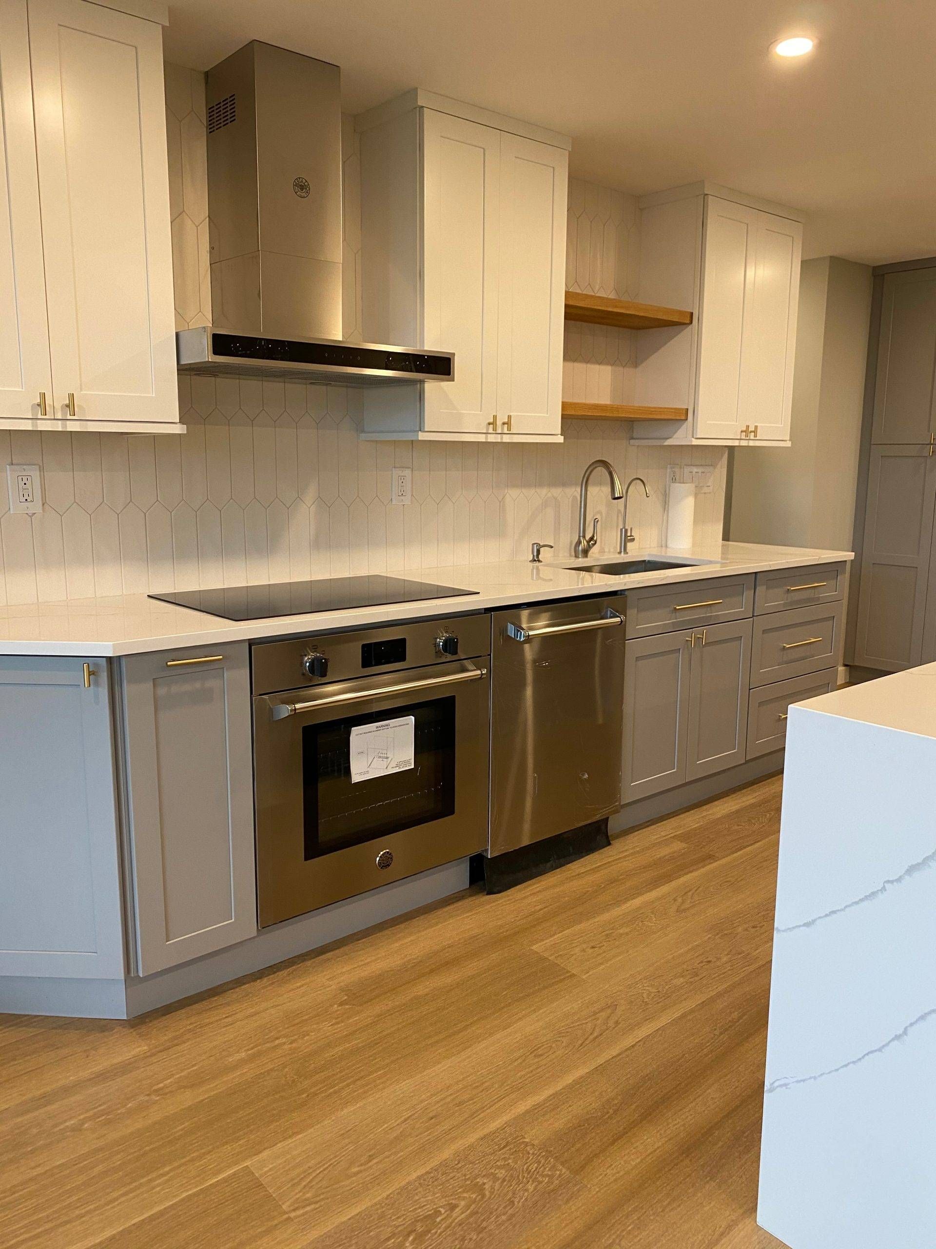 Modern kitchen with white cabinets, stainless steel appliances, and wood flooring