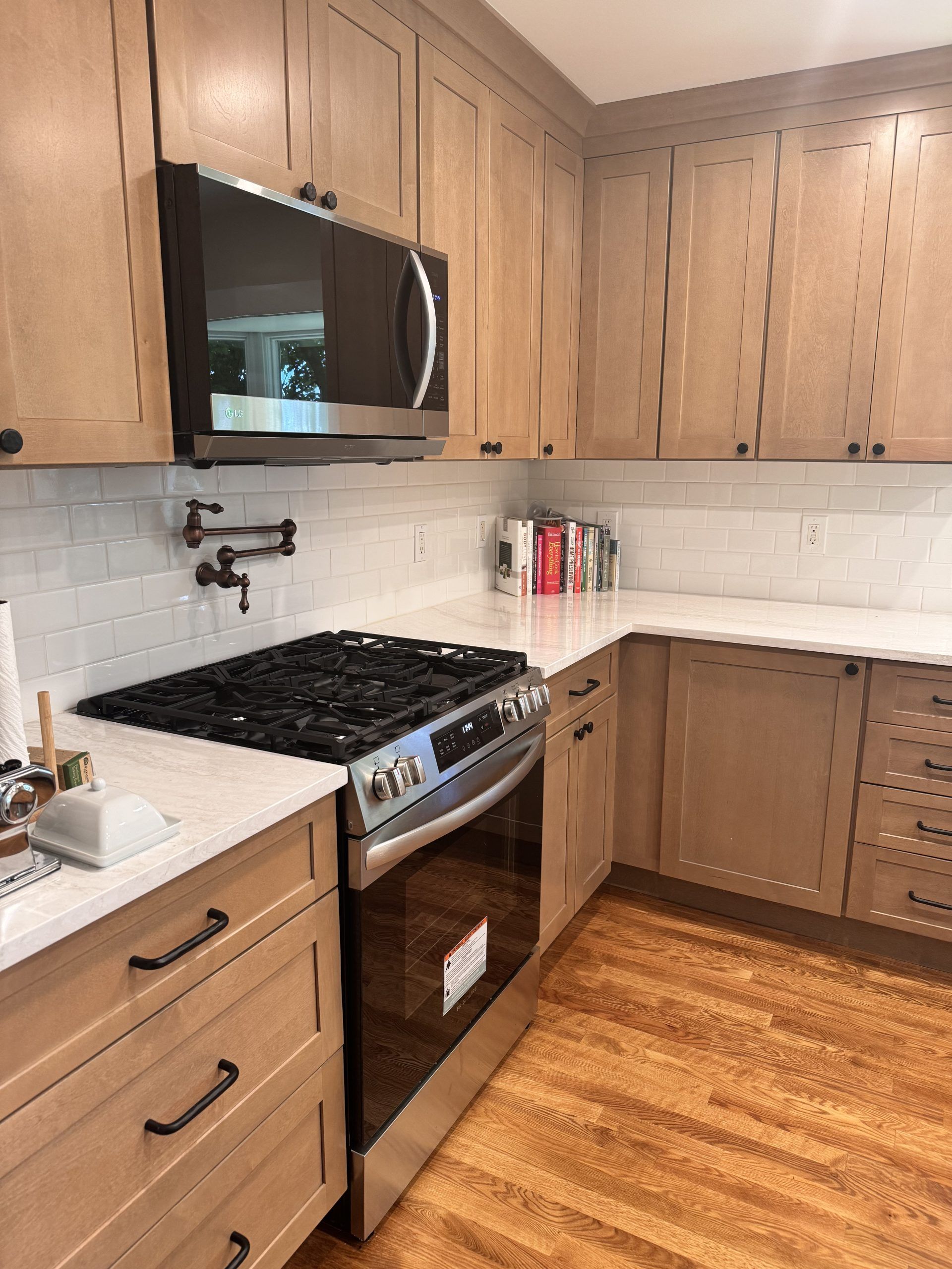Modern kitchen with wooden cabinets, black stove, white backsplash, and hardwood floor