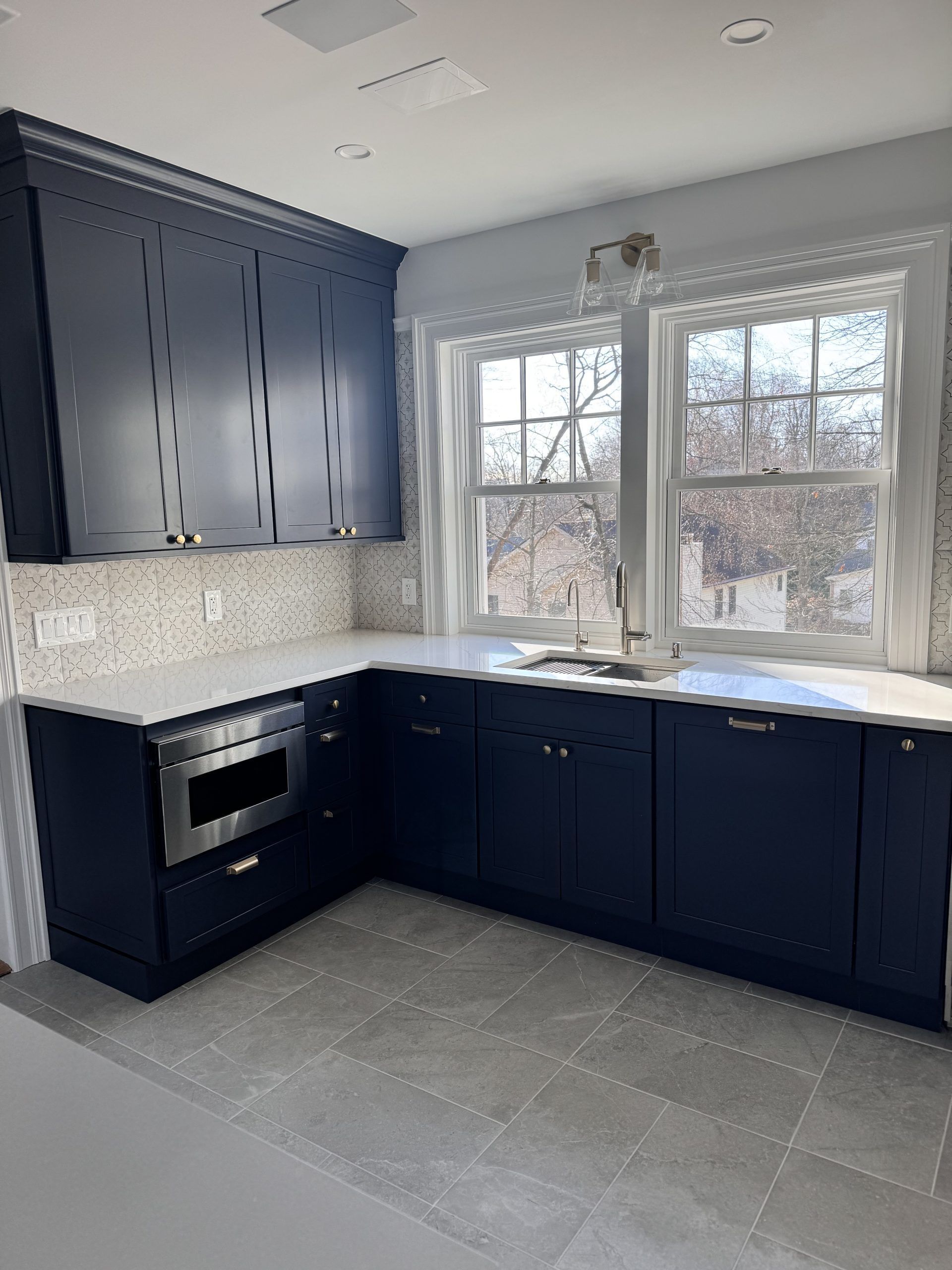 Modern kitchen with navy cabinets, gray tile floor, and large window over the sink