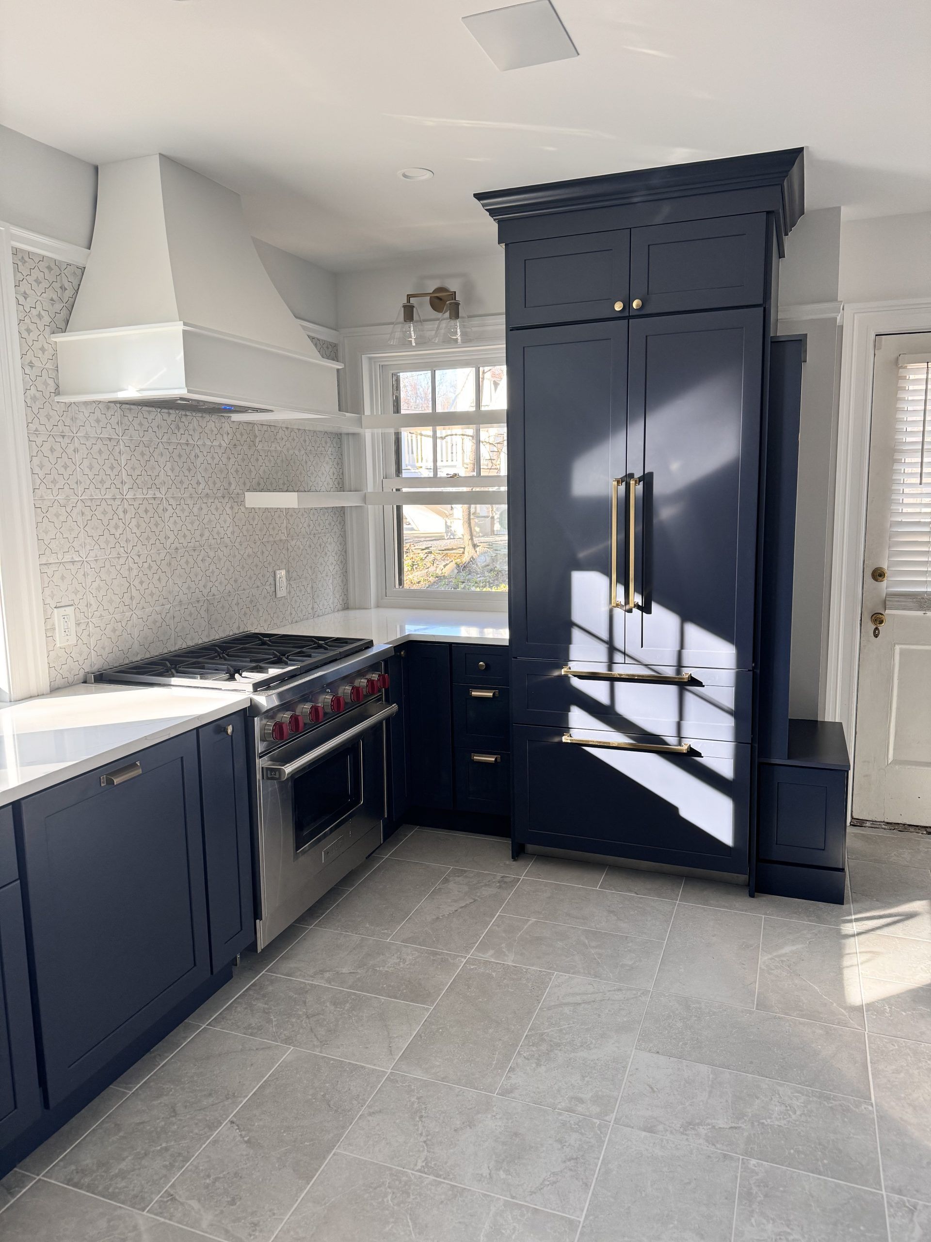 Modern kitchen with navy cabinets, white countertops, a large dark refrigerator, and light gray tile floor