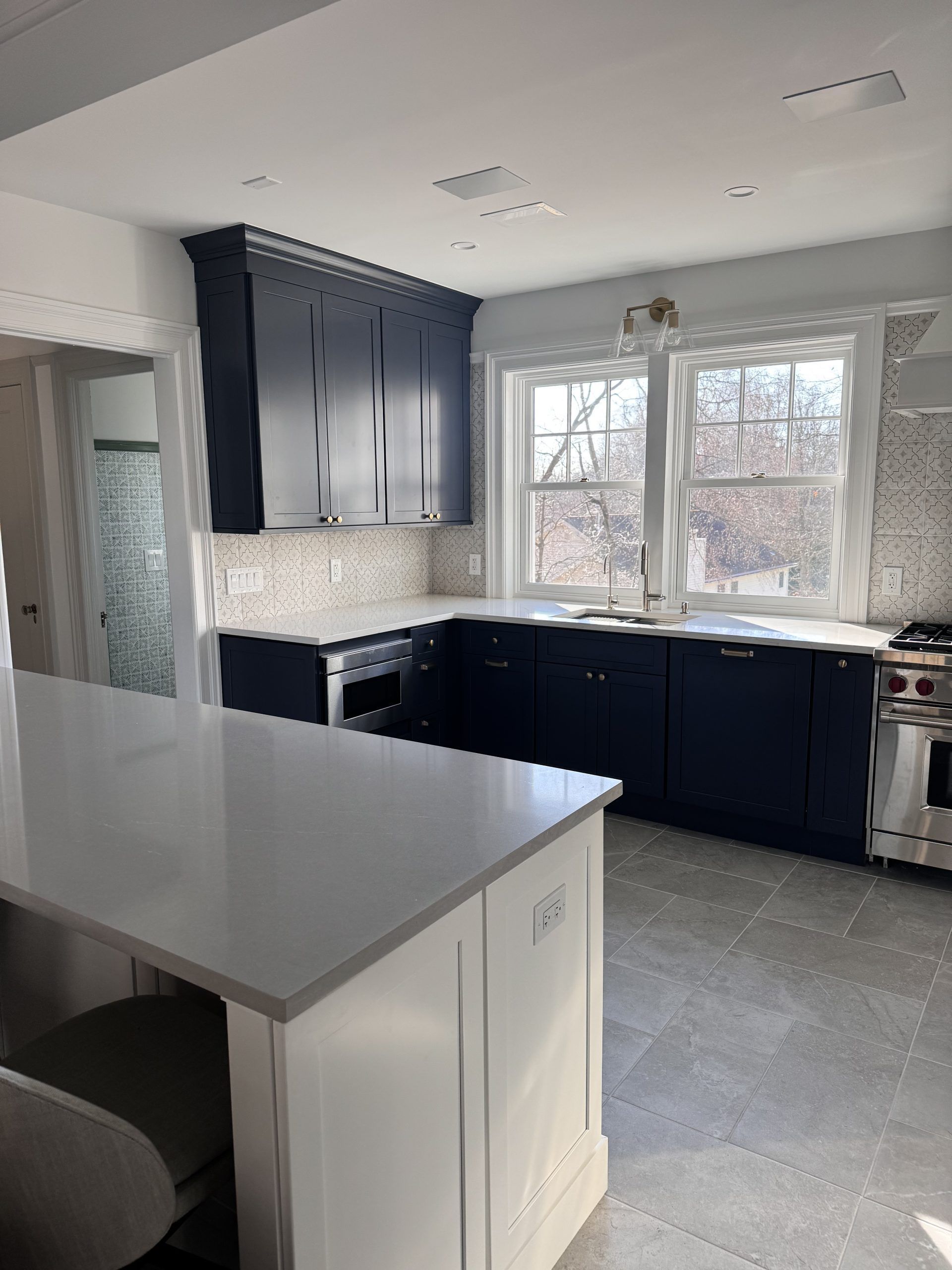 Bright kitchen with dark cabinets, white island, and large windows over the sink