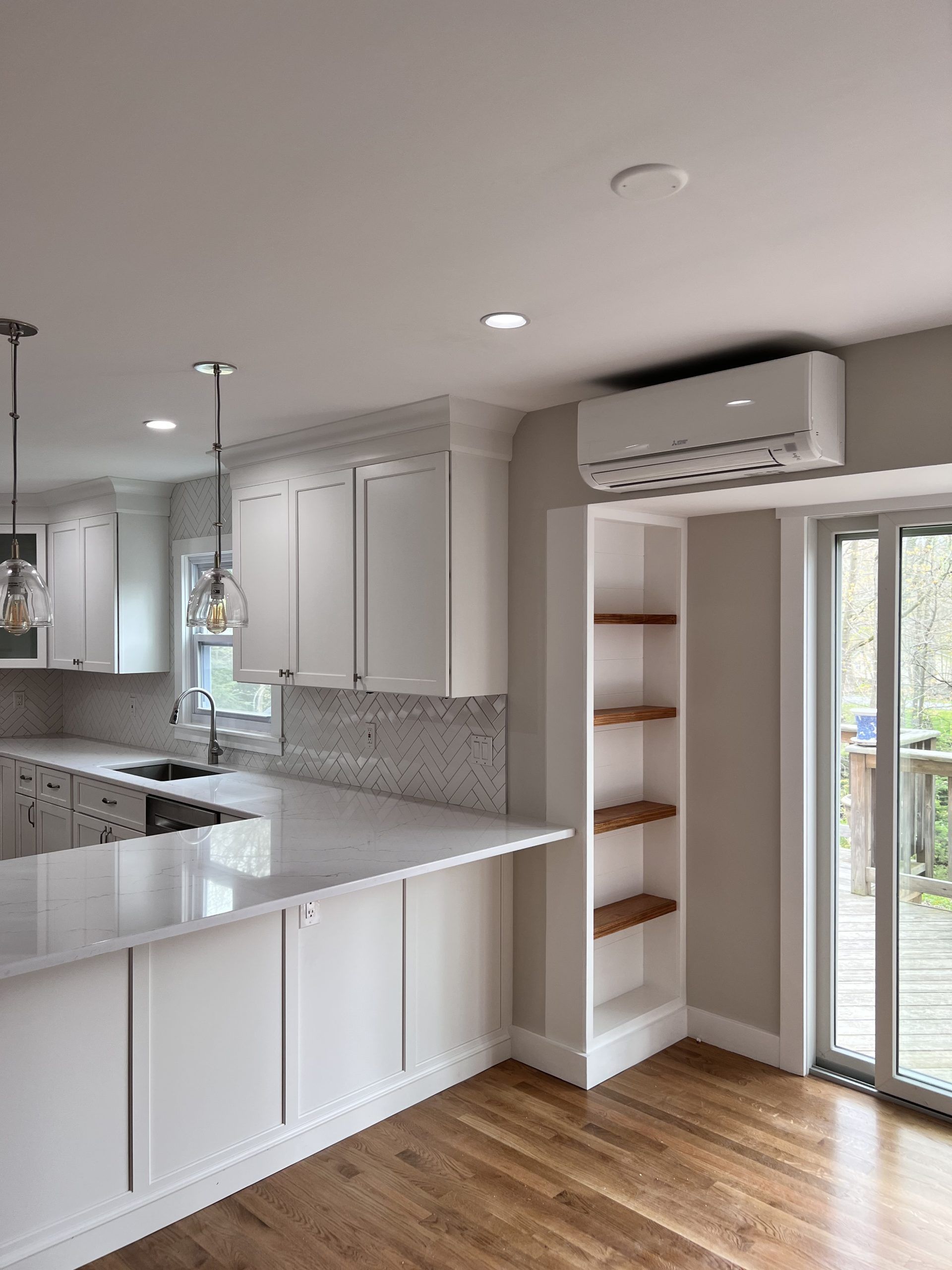 Bright modern kitchen with white cabinets, granite island, wood floor, and sliding glass door.