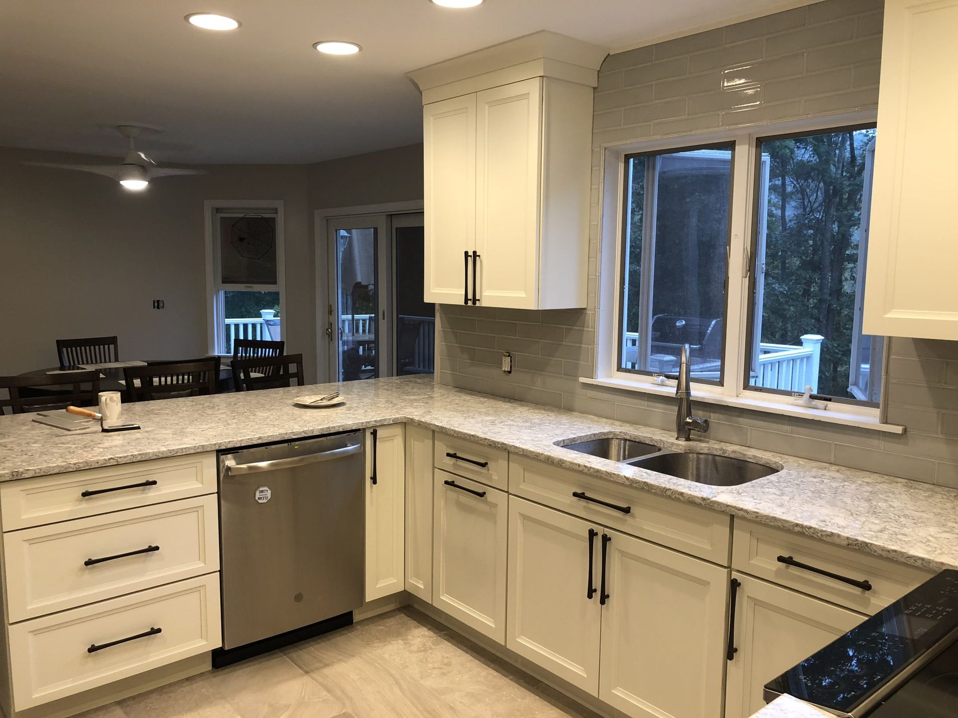 Modern kitchen with beige cabinets, granite countertops, stainless dishwasher, and large window over the sink