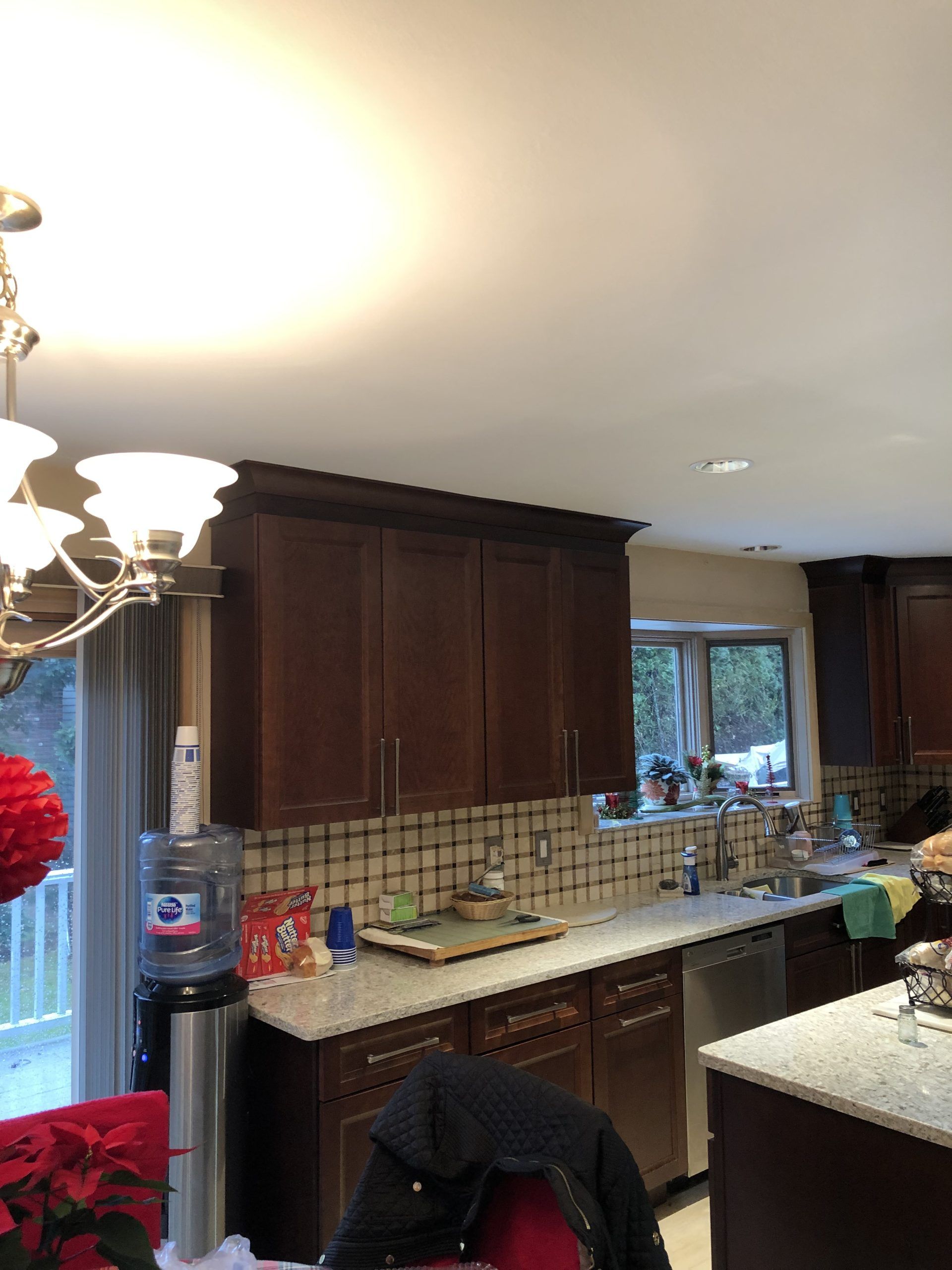 Kitchen with dark wood cabinets, tiled backsplash, granite counters, and a window above the sink.