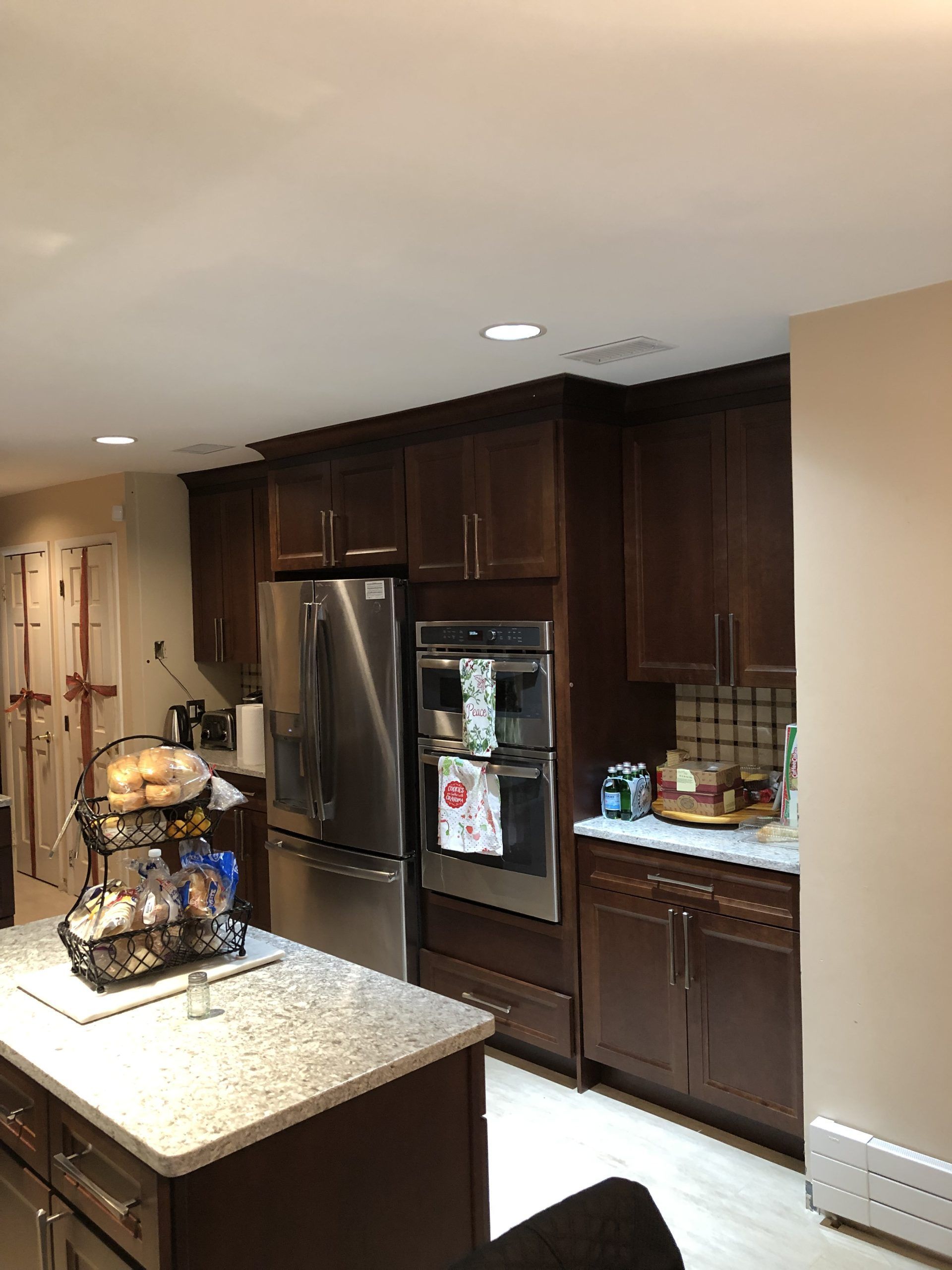 Modern kitchen with dark wood cabinets, stainless steel fridge, and granite island with decorative centerpiece