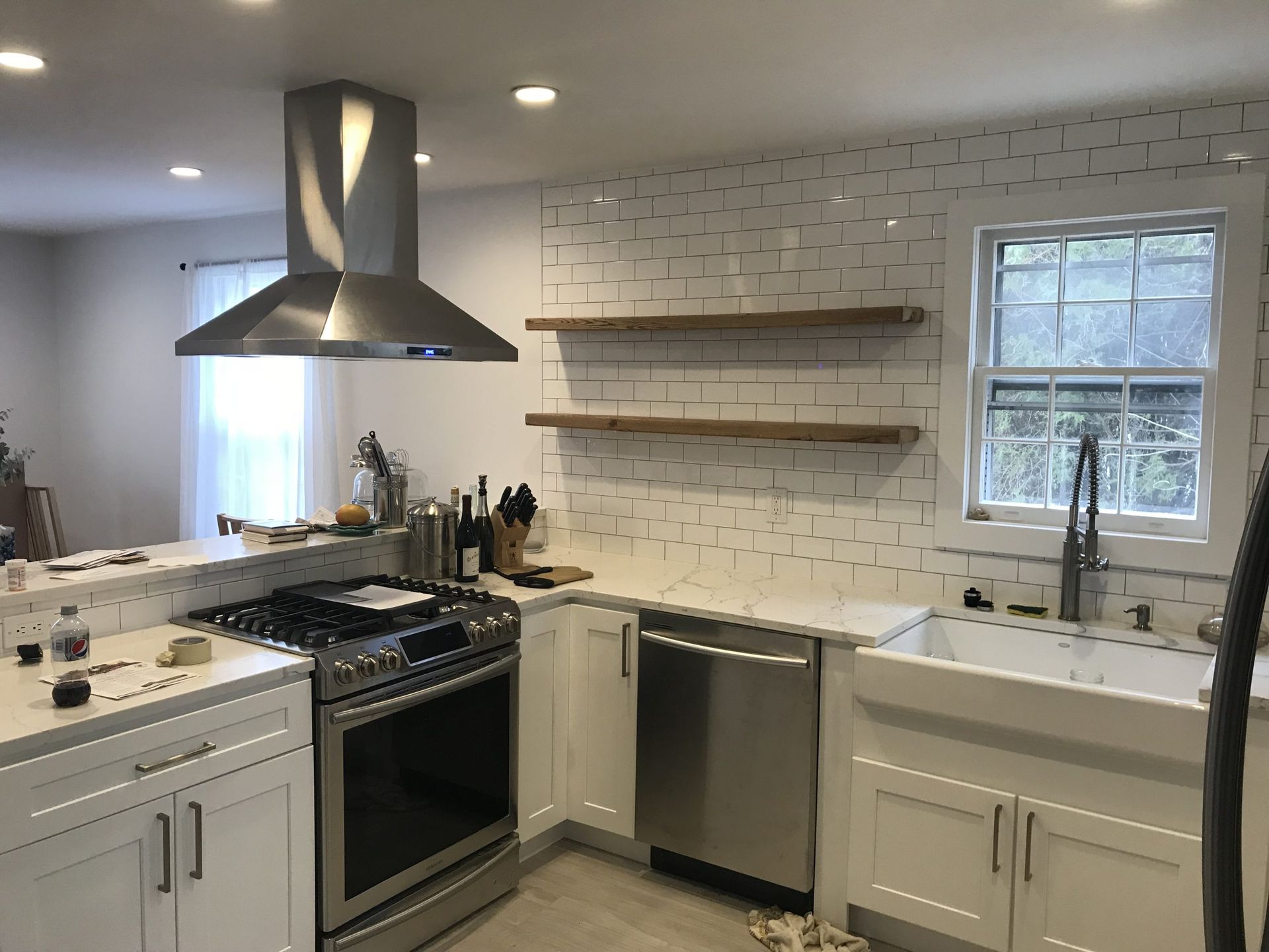 Bright modern kitchen with white cabinets, stainless appliances, tiled backsplash, and window over the sink