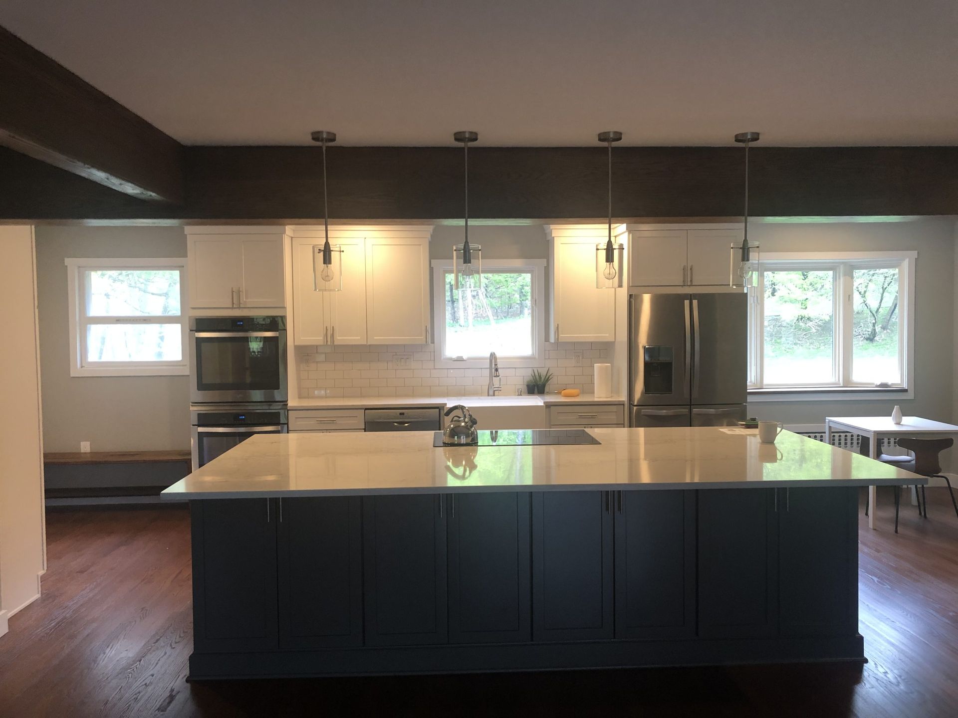 Modern kitchen with a large dark island, white countertops, pendant lights, and stainless steel appliances.